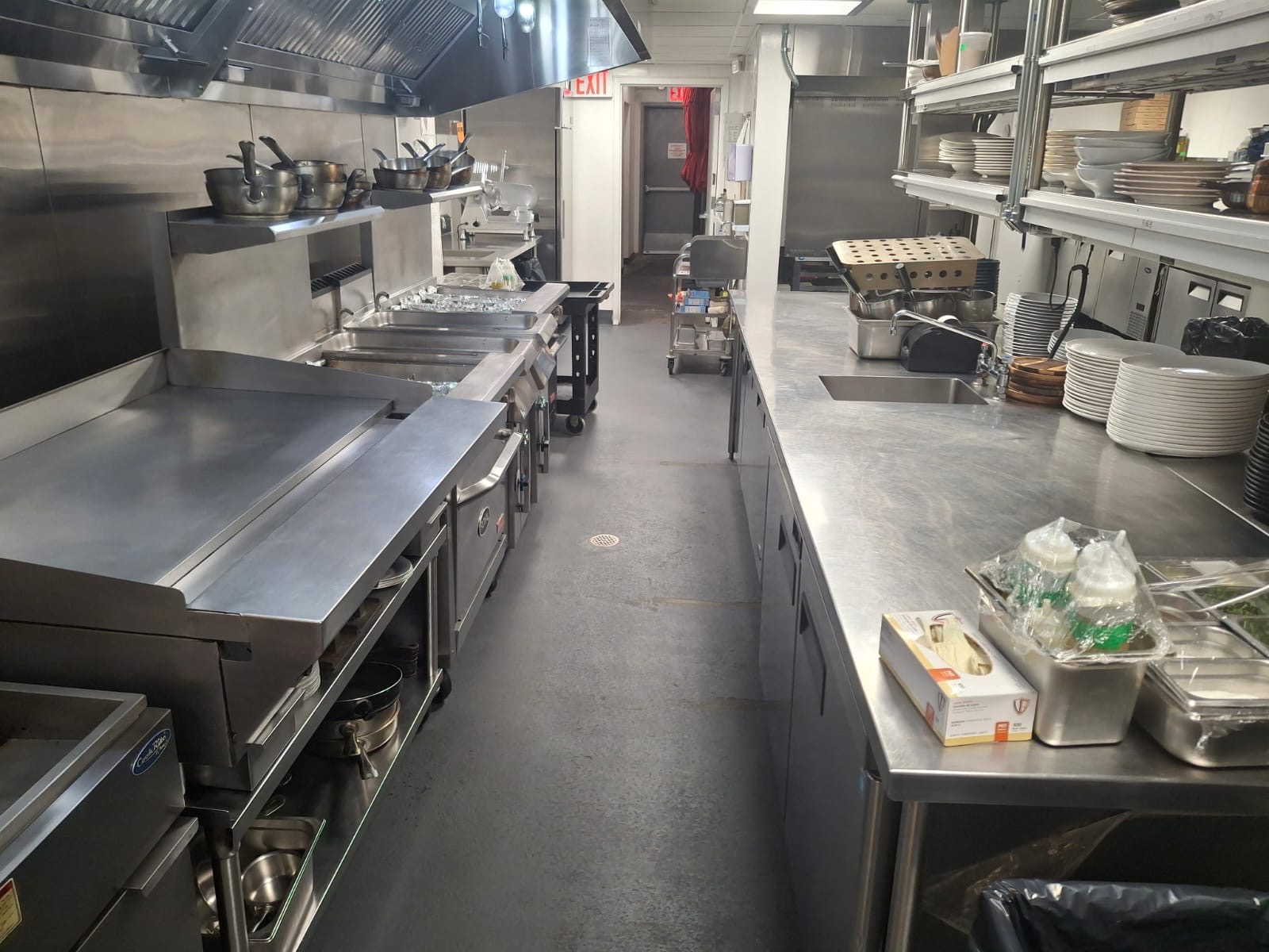 Long restaurant kitchen galley with wiped-down counters, clean floors and organized shelving — Ledian's Cleaning Services