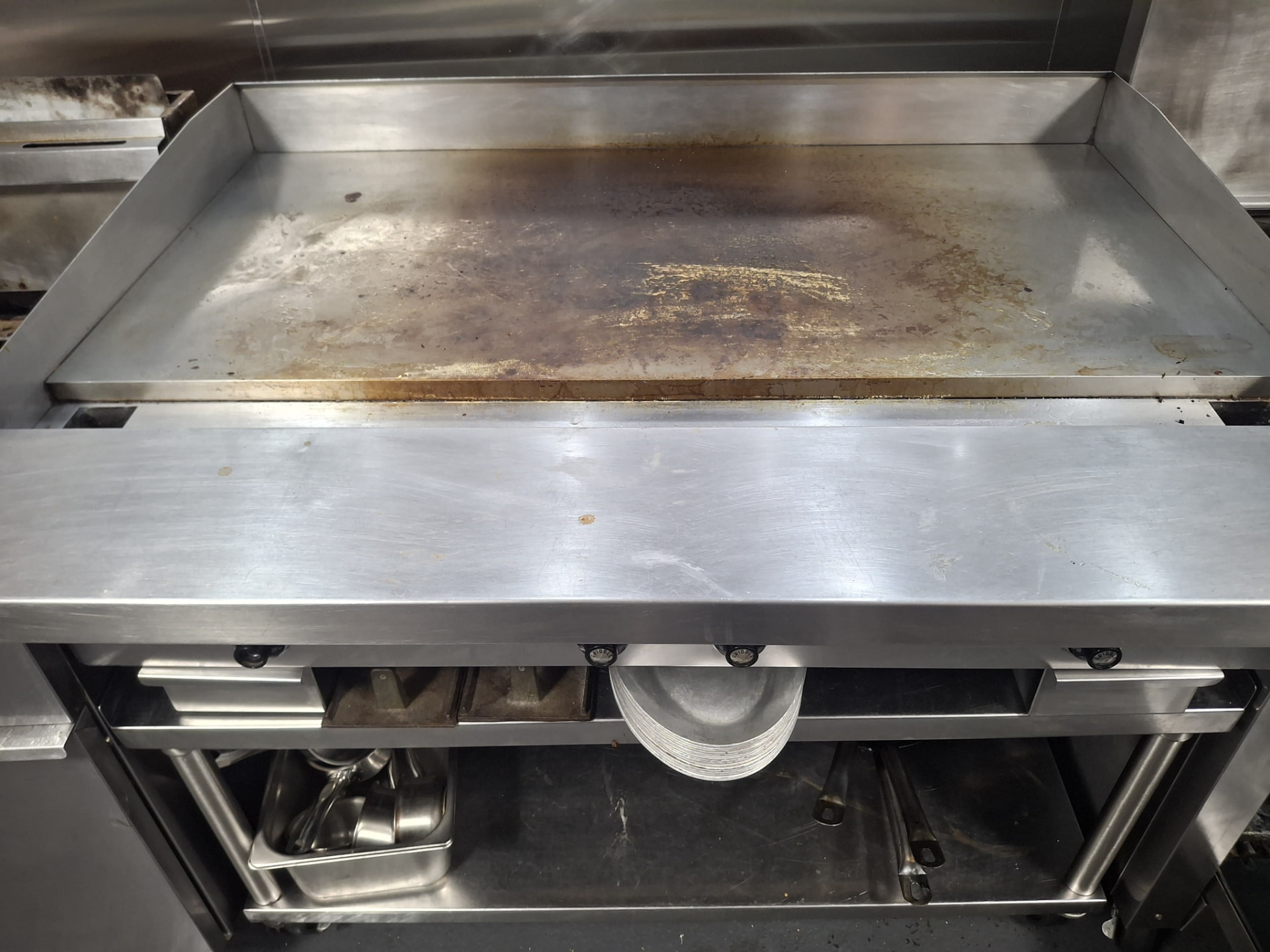 Restaurant flat-top griddle covered in burnt-on grease and food residue before cleaning by Ledian's Cleaning Services
