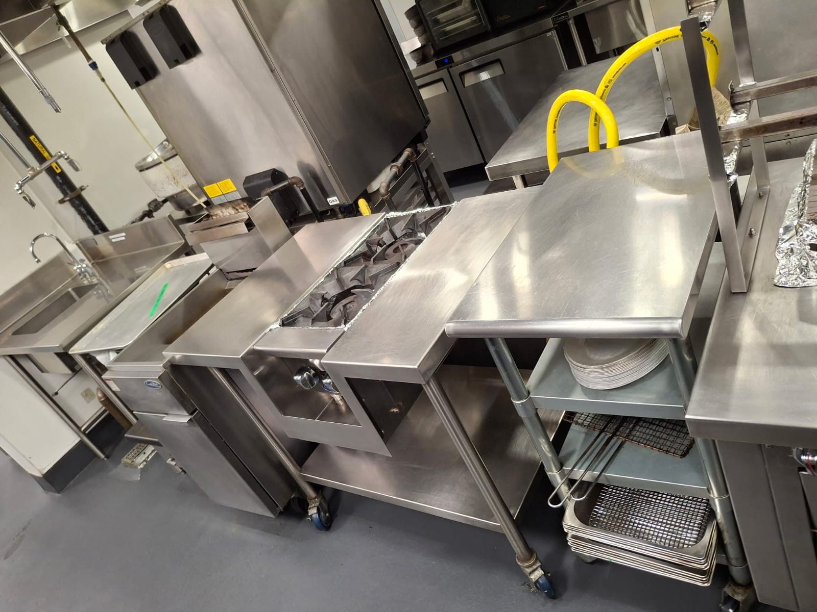 Sanitized kitchen station with scrubbed stove, prep tables and stacked pans — Ledian's Cleaning Services