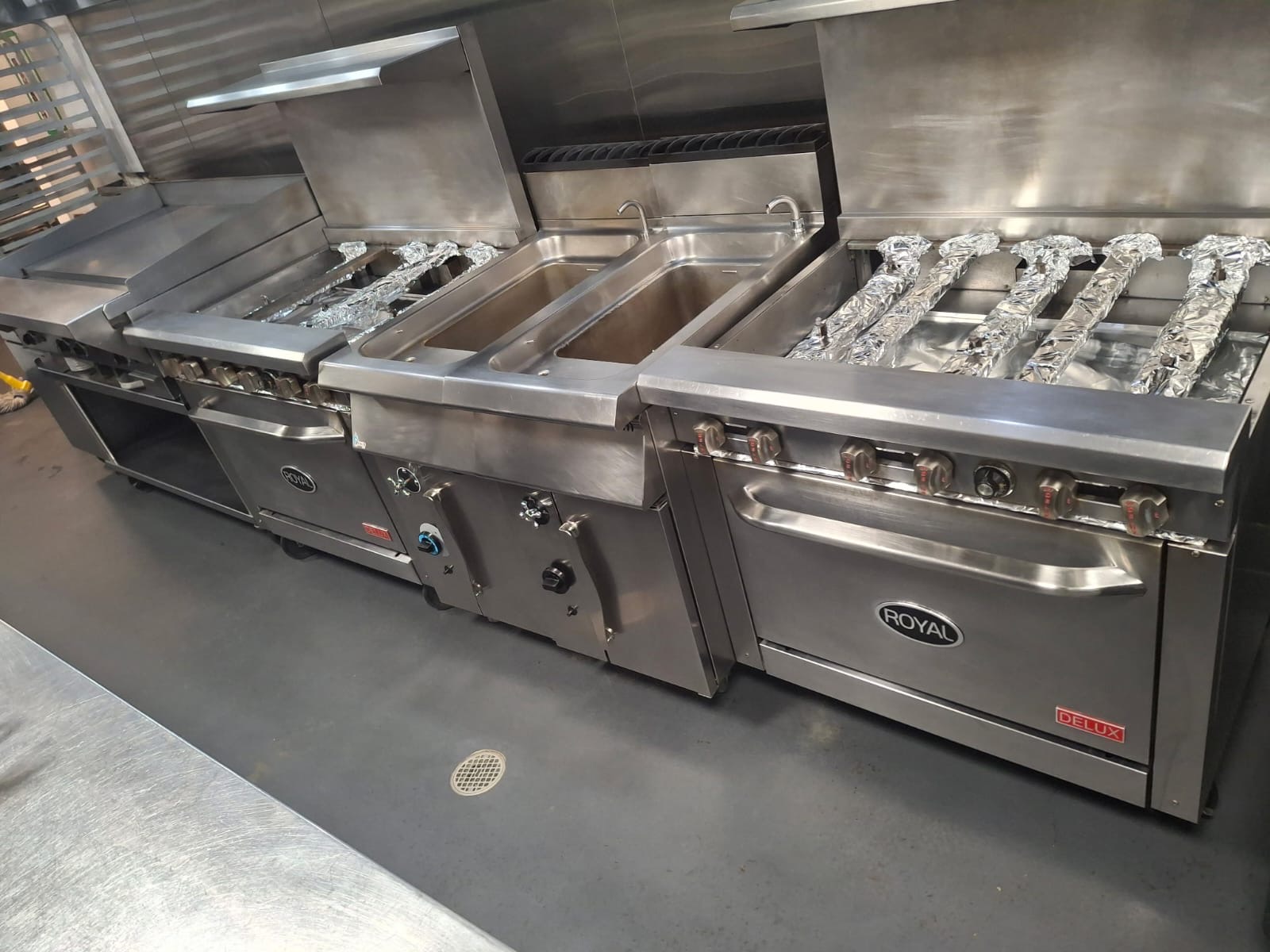 Spotless commercial kitchen line with polished stainless steel prep counters — Ledian's Cleaning Services