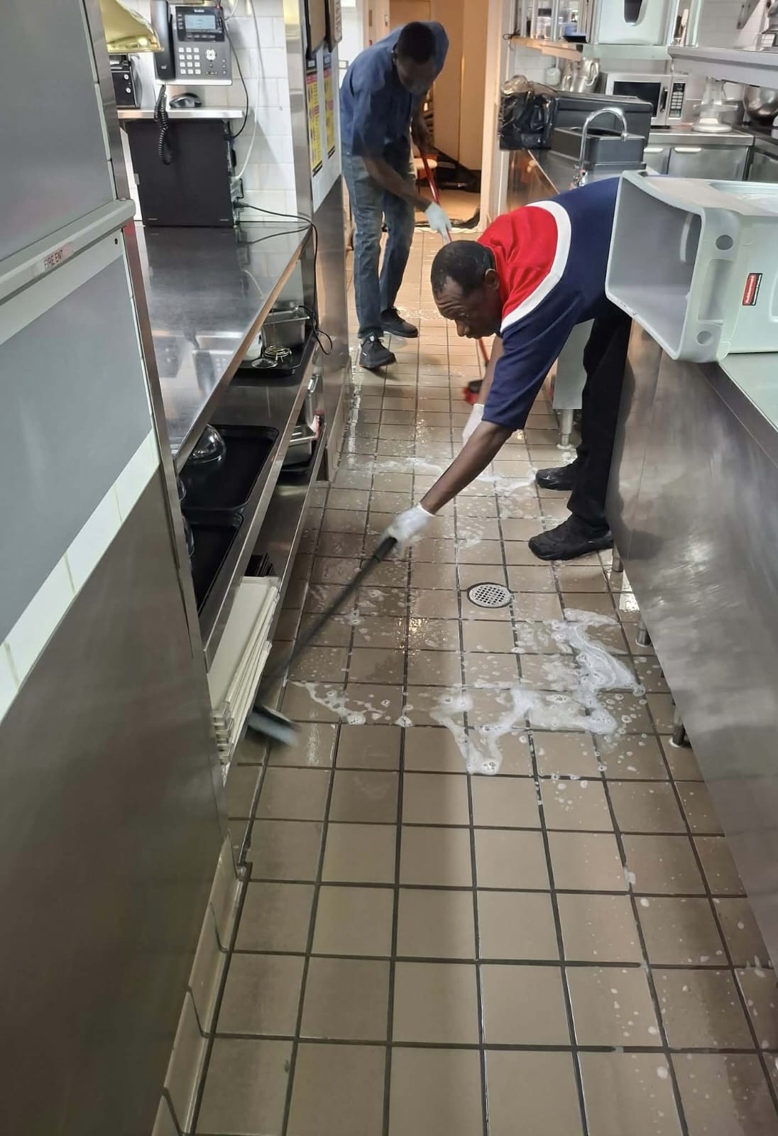 Ledian's Cleaning Services team scrubbing a commercial kitchen floor