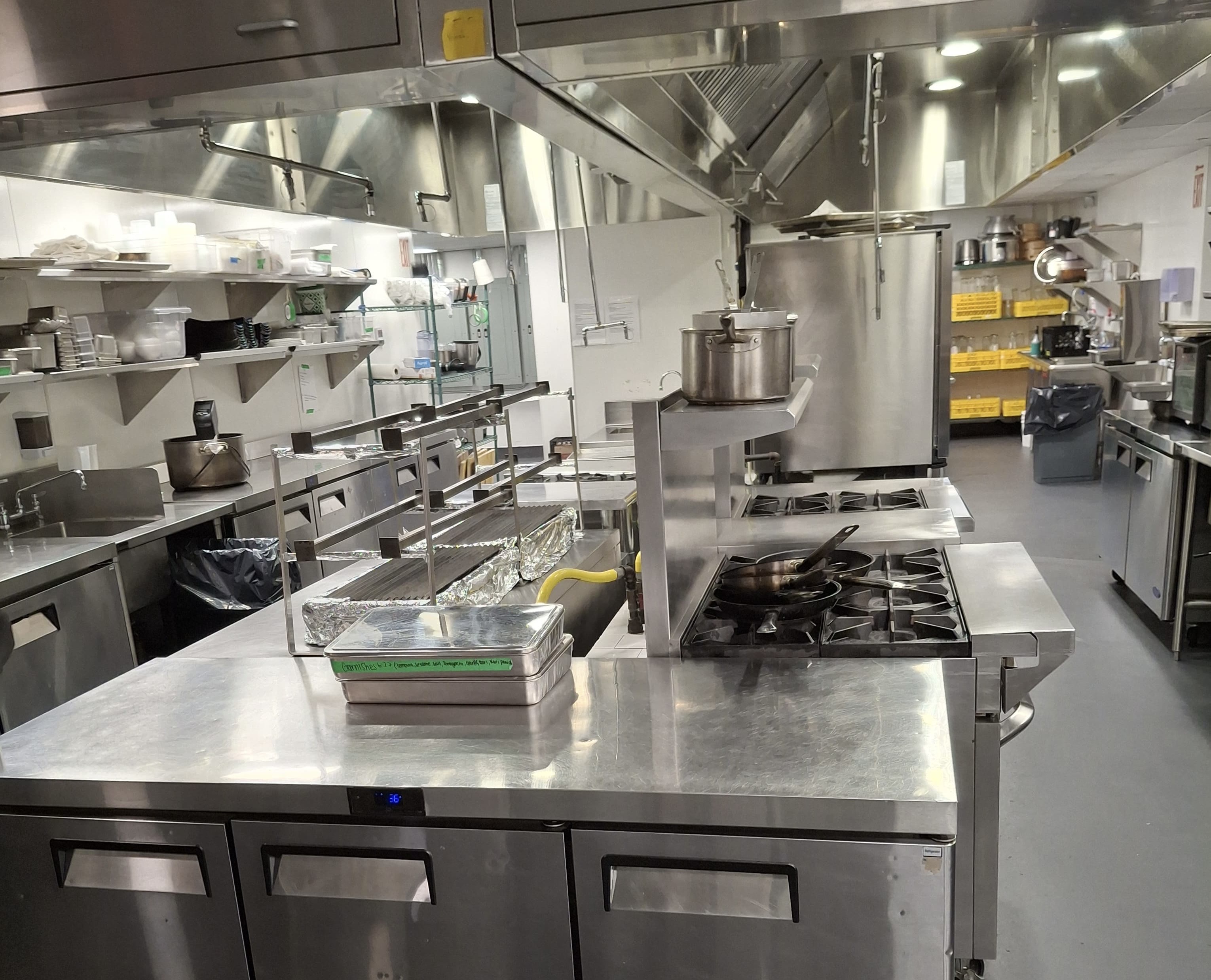 Restaurant kitchen after a deep clean, with gleaming range, hood and prep areas — Ledian's Cleaning Services